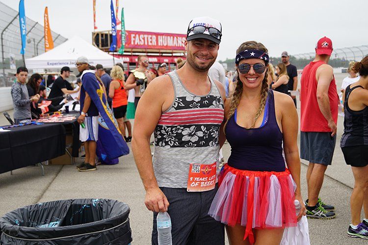 A man and a woman are posing for a picture at a race track.