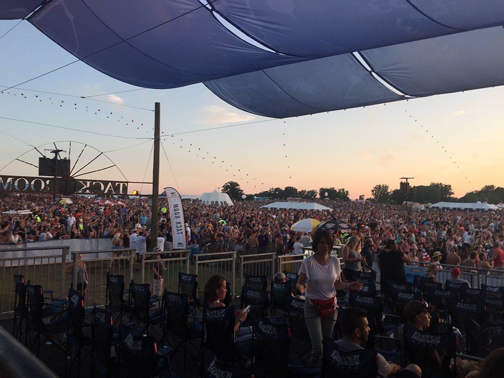 A crowd of people are gathered under an umbrella at a music festival