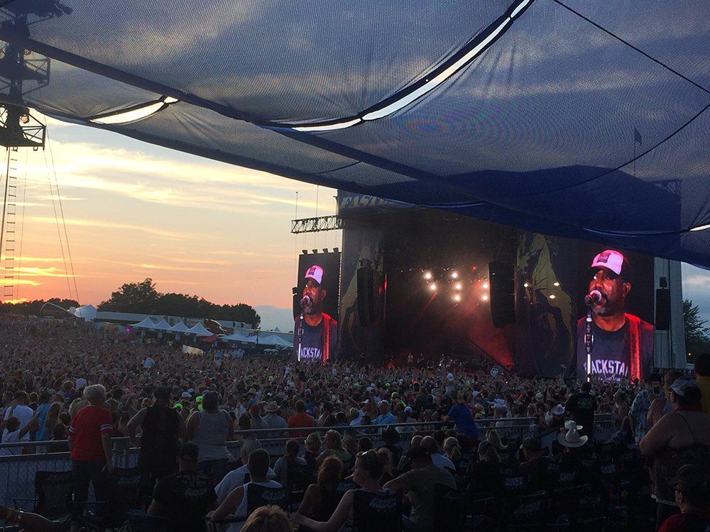 A crowd of people are sitting in front of a stage at a concert.