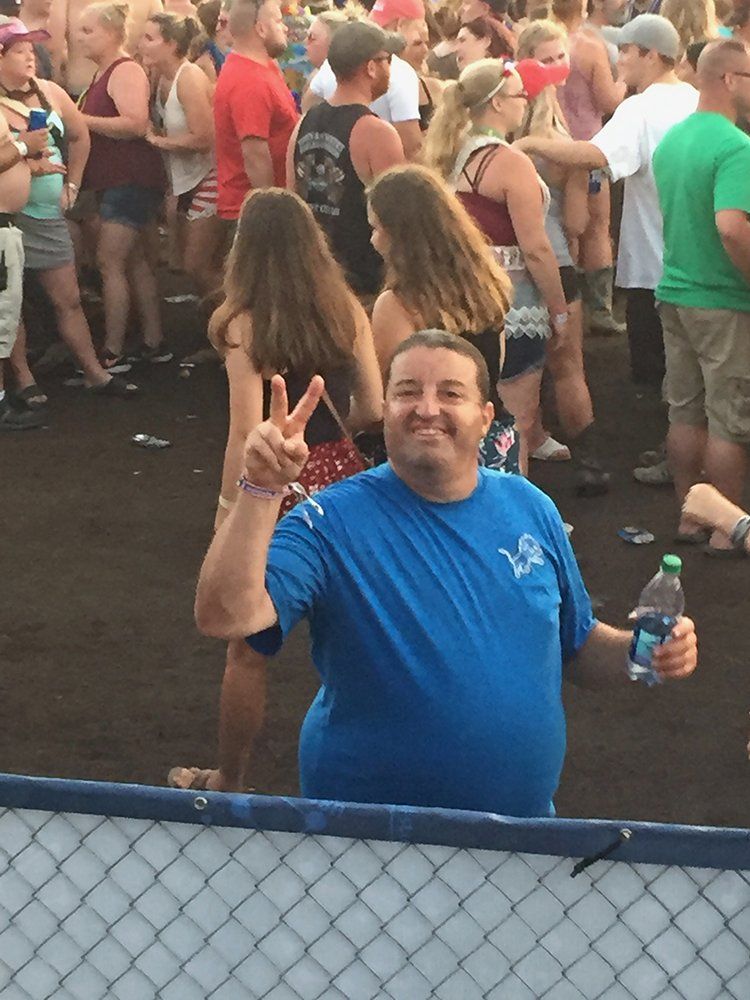 A man in a blue shirt is holding a bottle of water in front of a crowd of people.