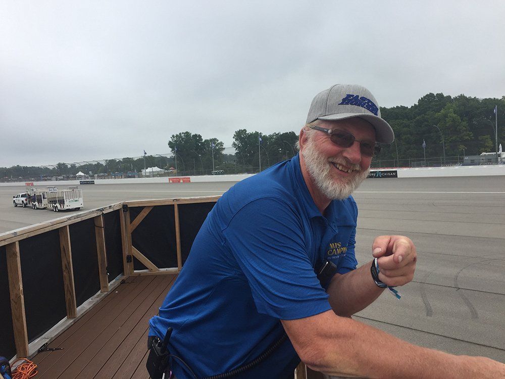 A man wearing a blue shirt and a hat with the word racing on it