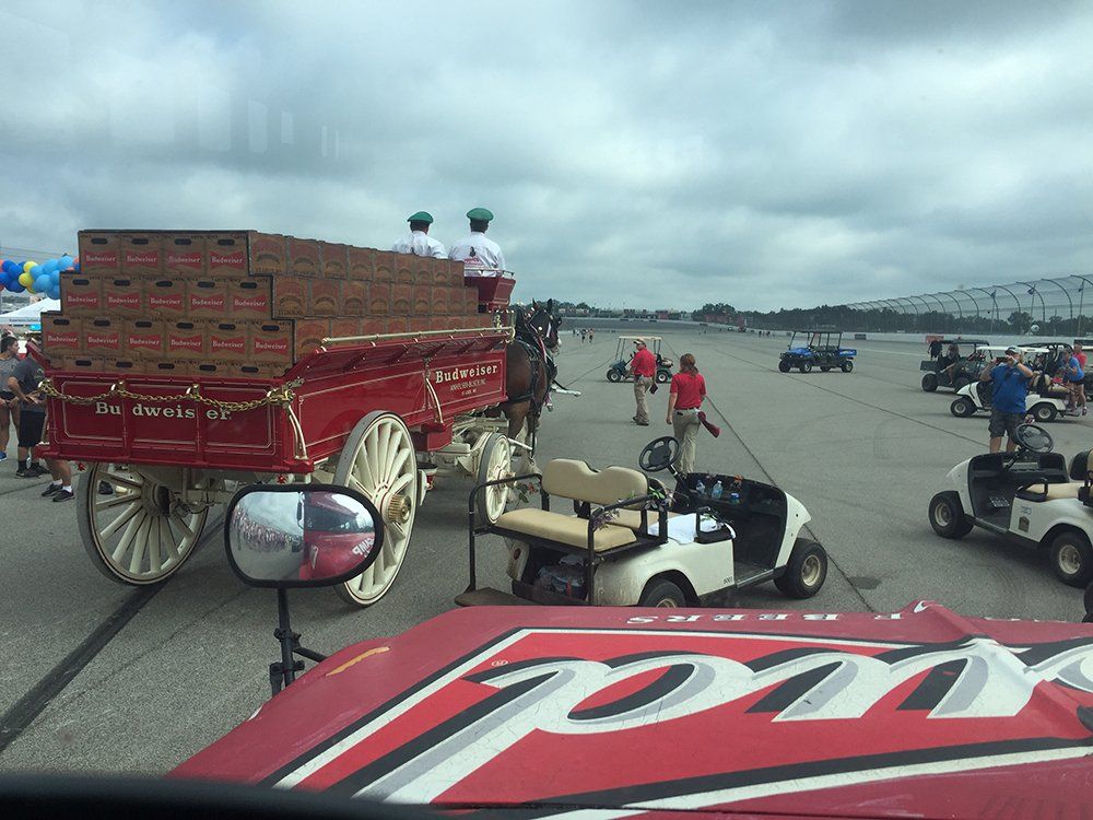 A horse drawn carriage filled with pizza boxes is parked in a parking lot.