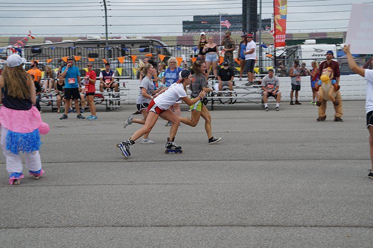 A group of people are rollerblading on a street in front of a crowd.