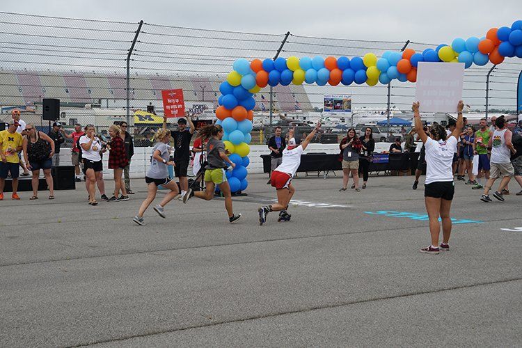 A group of people are running under an arch of balloons