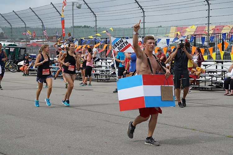 A man without a shirt is holding a flag in front of a crowd of people.
