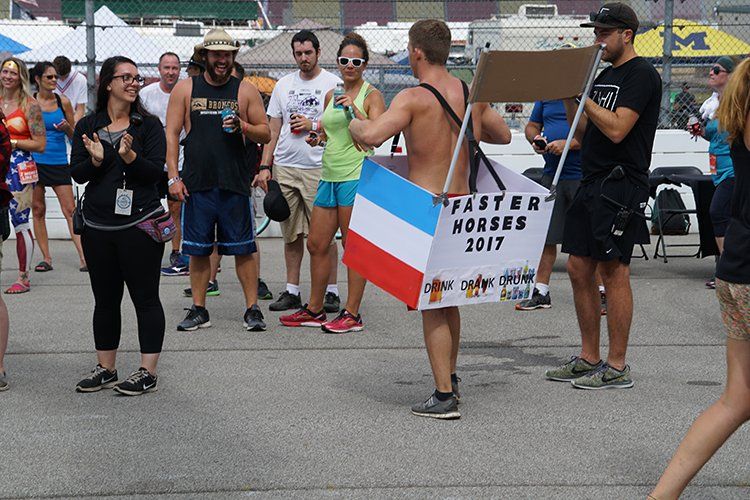 A man holding a sign that says faster horses 2017