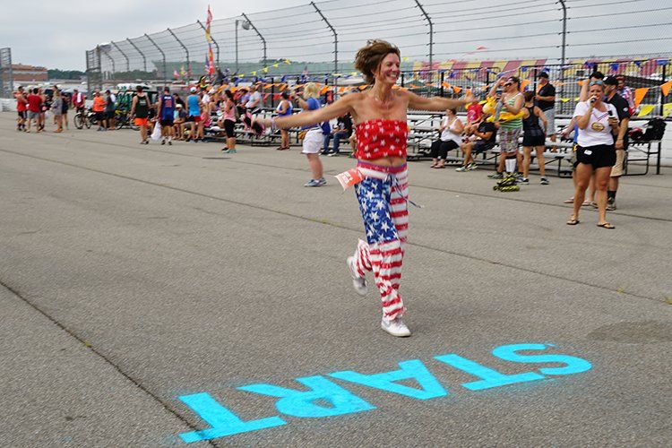 A woman is running on a race track with the word start painted on the ground