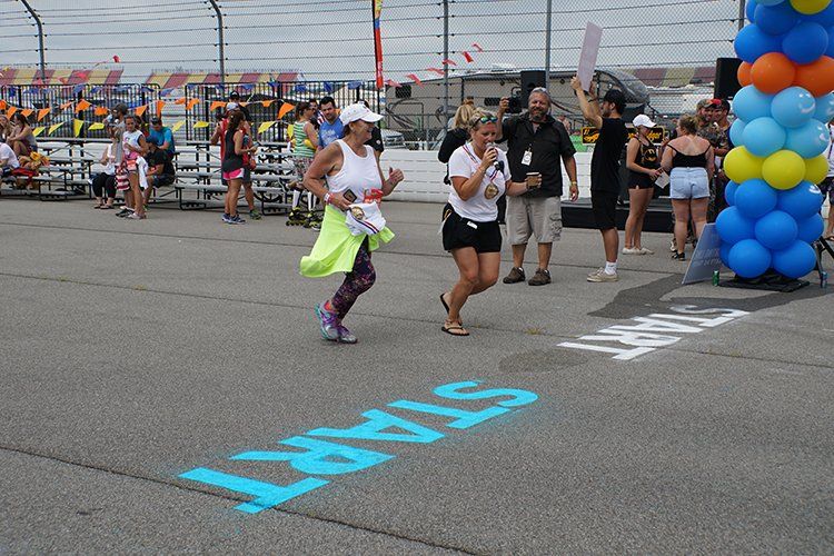 A woman is running in front of a sign that says start