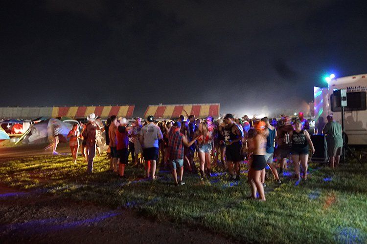 A large group of people are standing in a field at night.