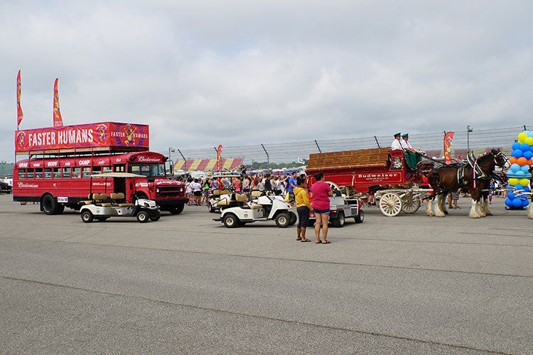 A horse drawn carriage is pulling a red bus at a carnival