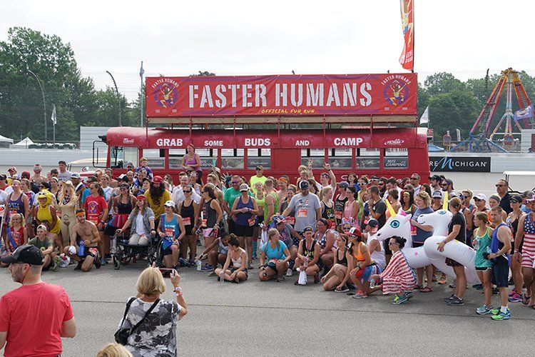 A large group of people are gathered in front of a sign that says faster humans