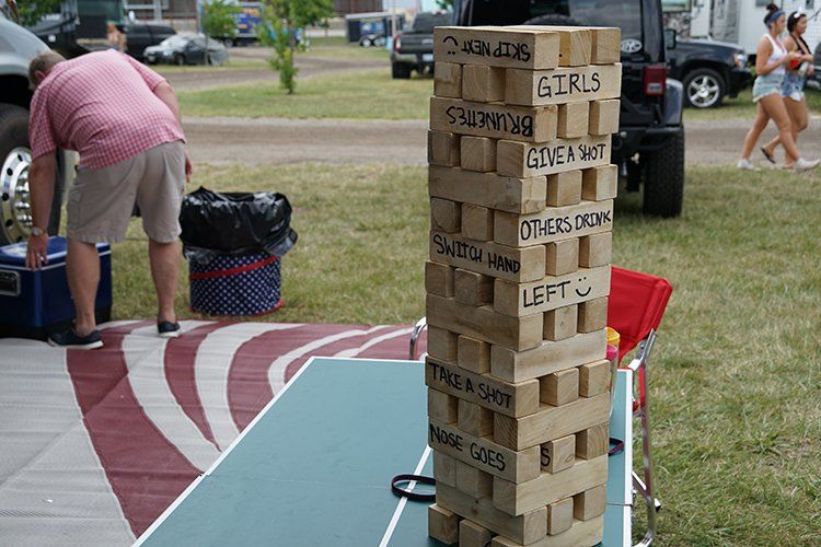 A man is standing next to a giant wooden jenga tower