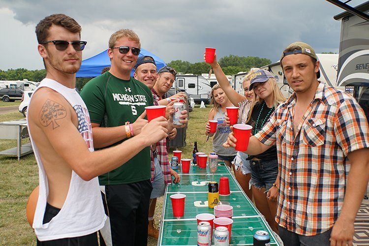 A group of people are standing around a table holding red cups.