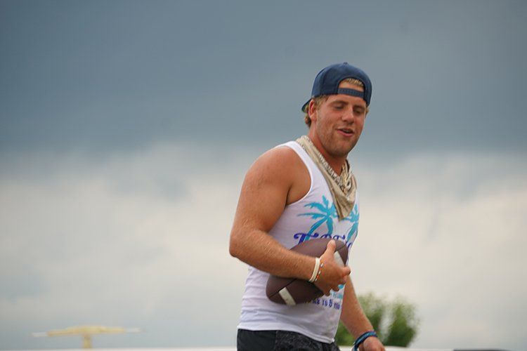 A man in a tank top is holding a football.