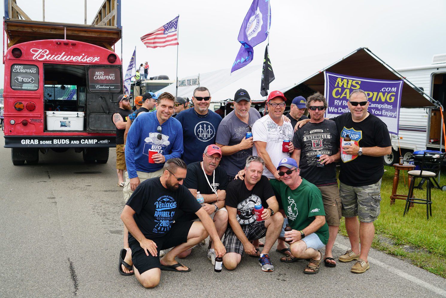 A group of men posing for a picture in front of a budweiser truck