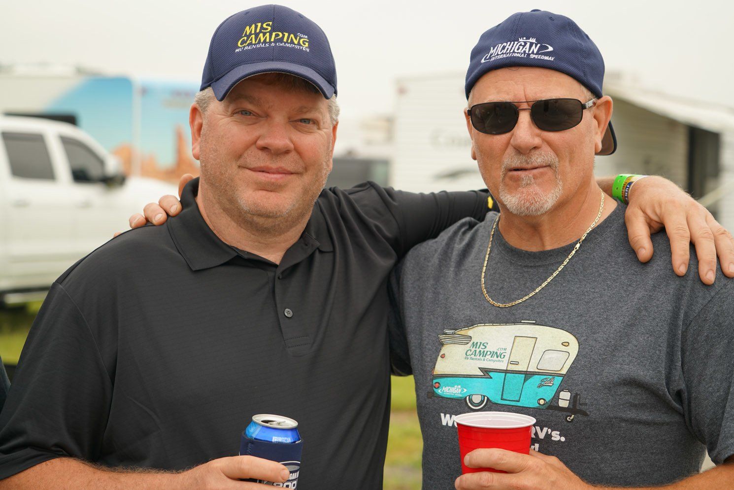 Two men posing for a picture with one wearing a shirt that says his camping