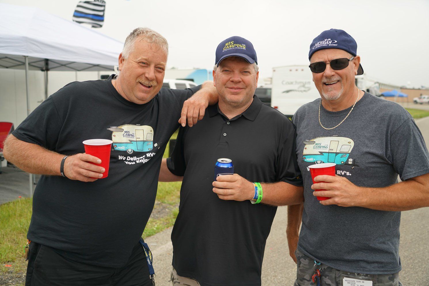 Three men are posing for a picture while drinking beer