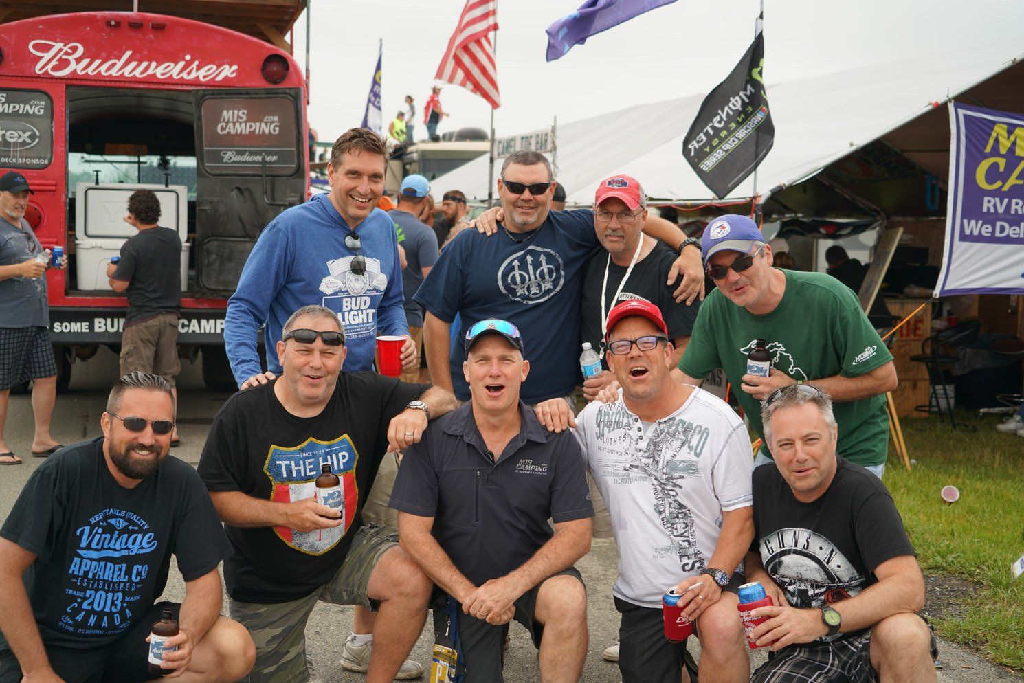 A group of men posing for a picture in front of a budweiser truck