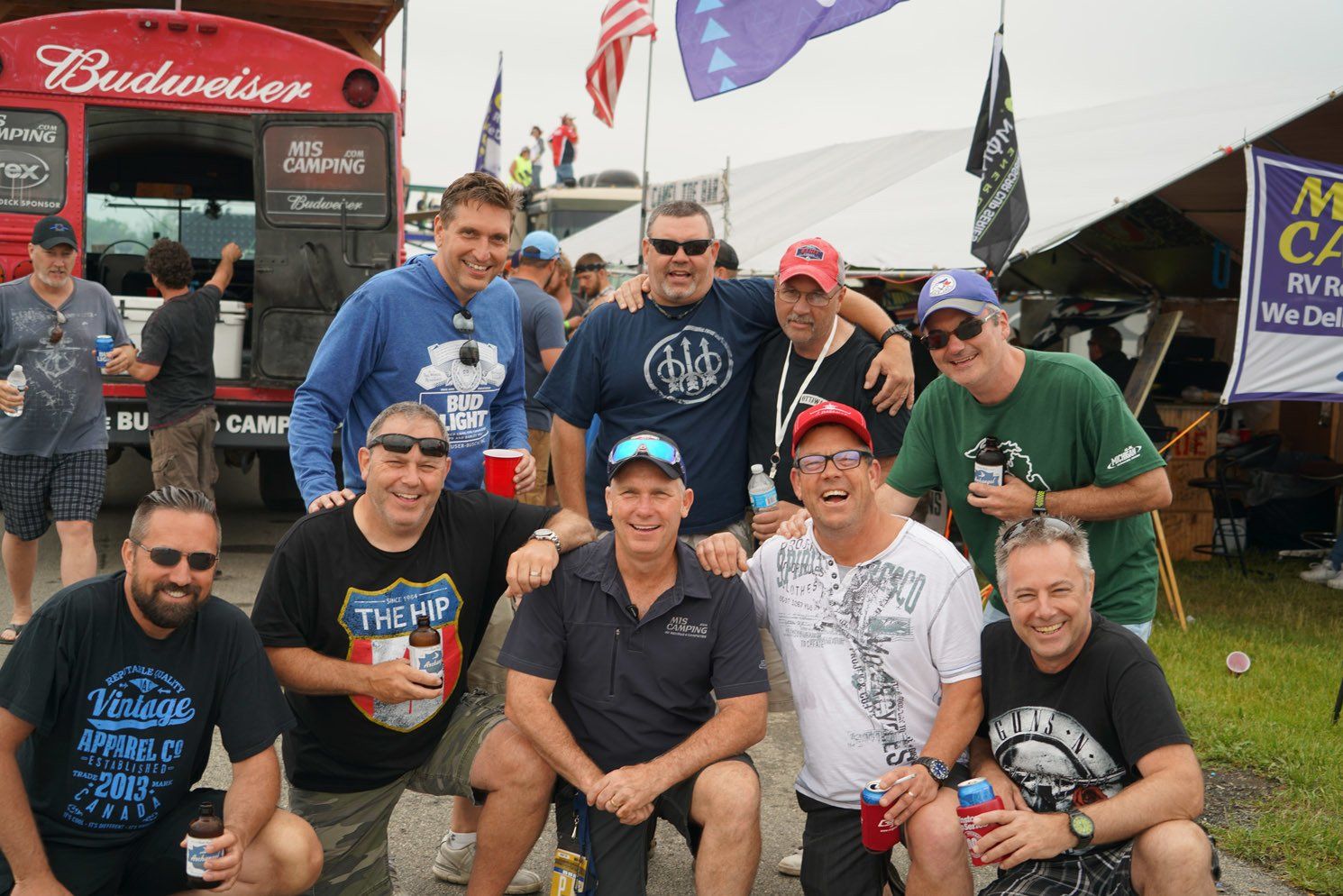 A group of men posing for a picture in front of a budweiser truck