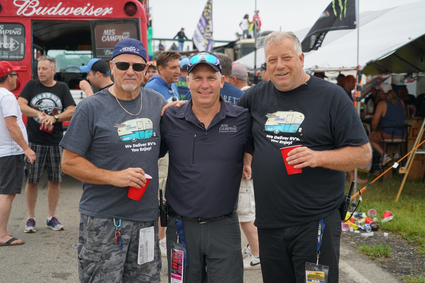 Three men are posing for a picture in front of a budweiser truck