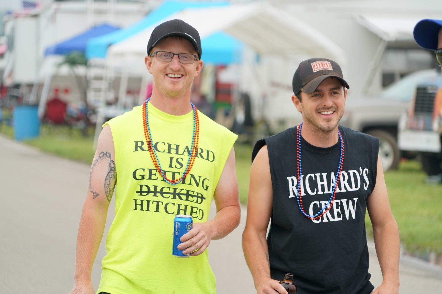 Two men wearing shirts that say richard 's crew are walking down a street.