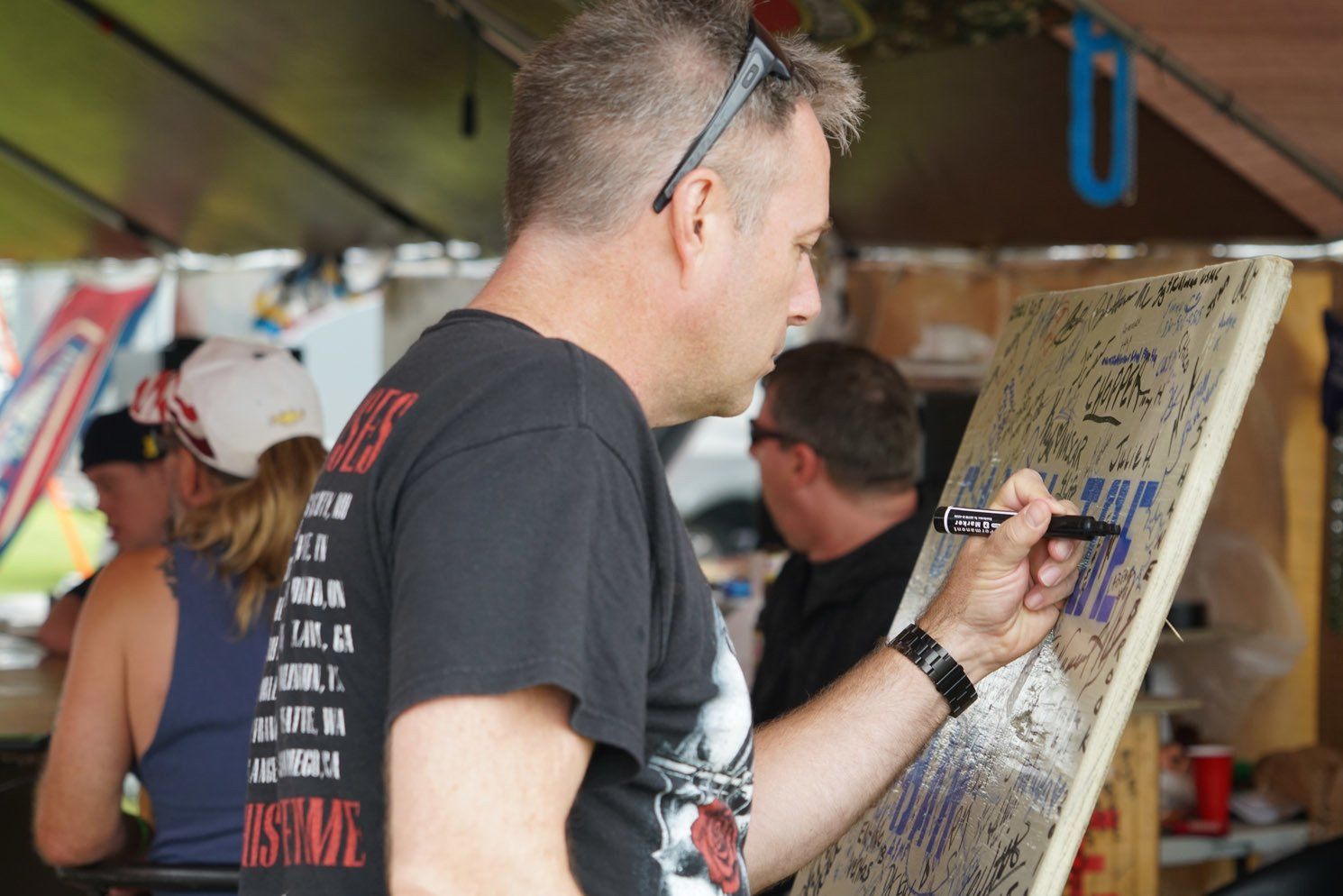 A man in a black shirt that says absolute is writing on a board