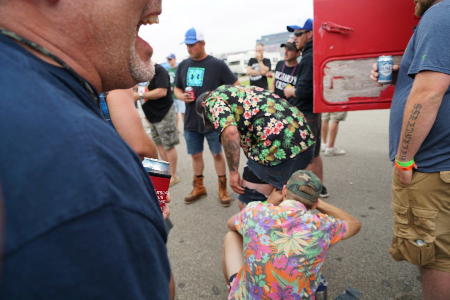 A group of men are standing around a man in a hawaiian shirt