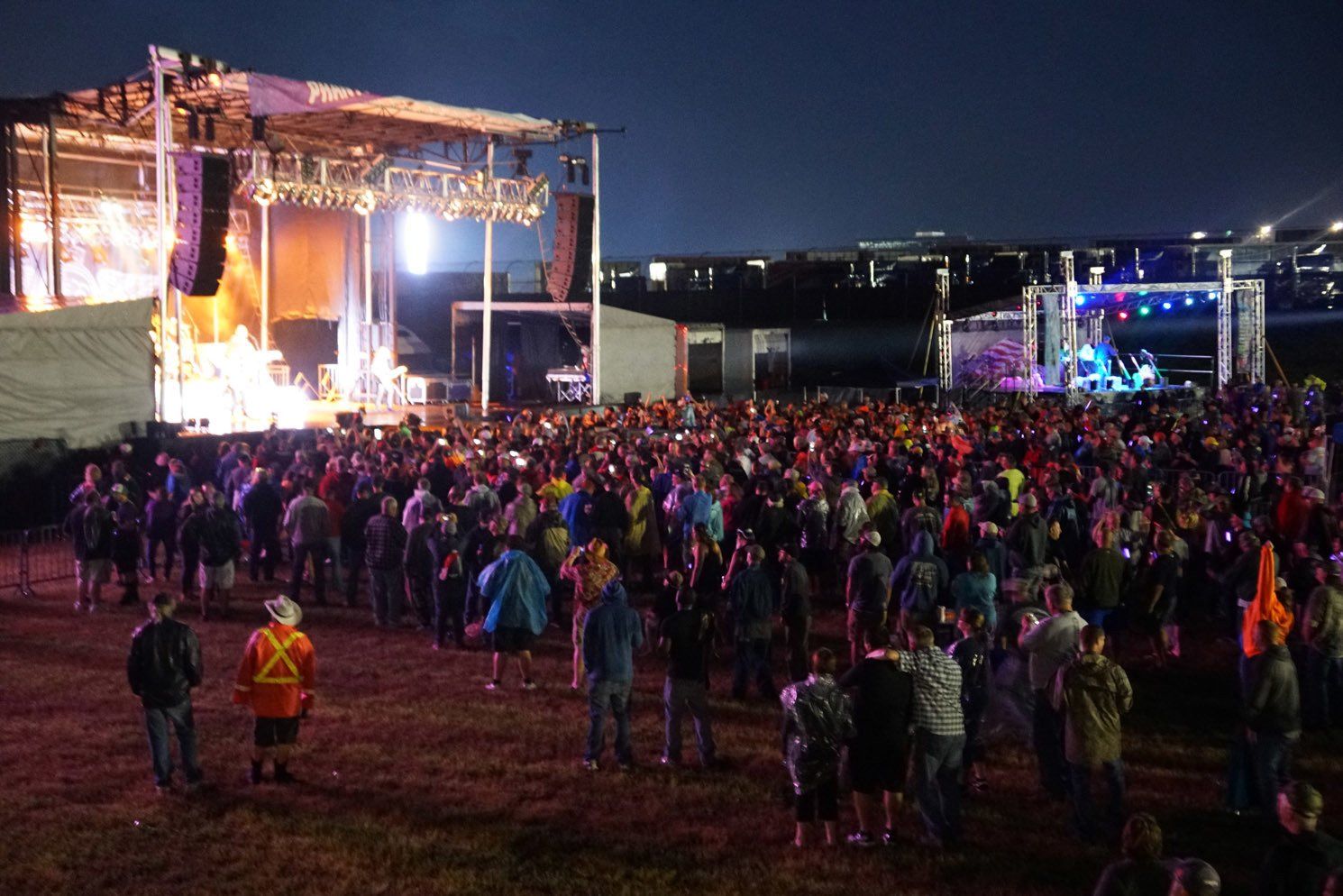 A crowd of people are standing in front of a stage at a concert.