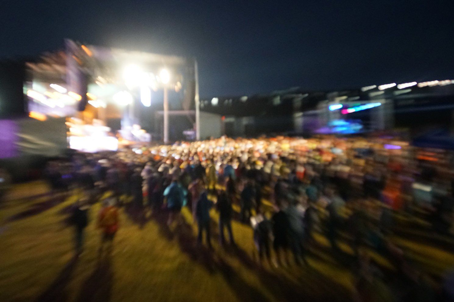 A blurry picture of a crowd of people at a concert at night.