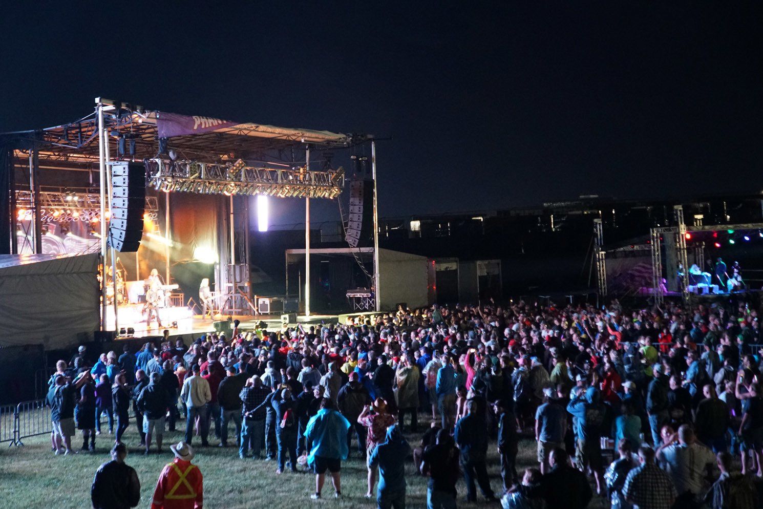 A large crowd of people are standing in front of a stage at a concert.