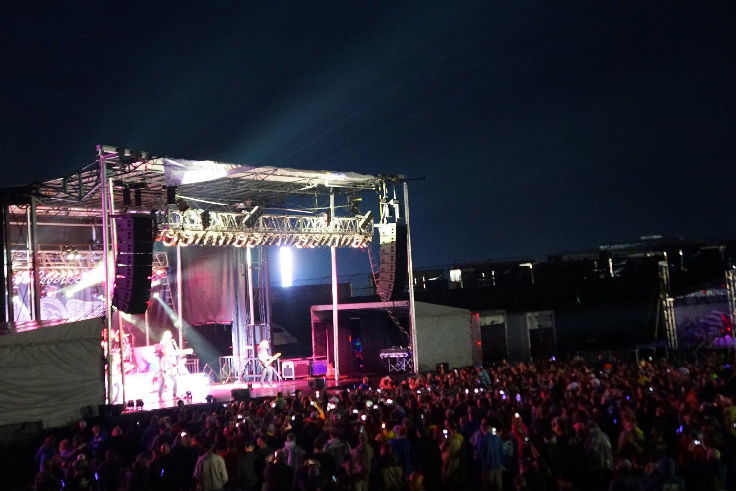 A crowd of people watching a band on stage at night