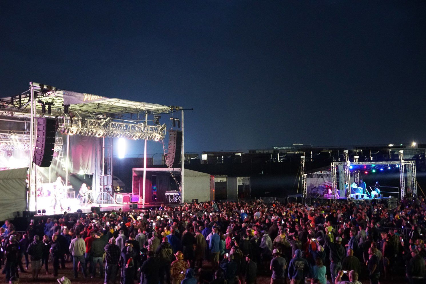 A large crowd of people are standing in front of a stage at a concert.