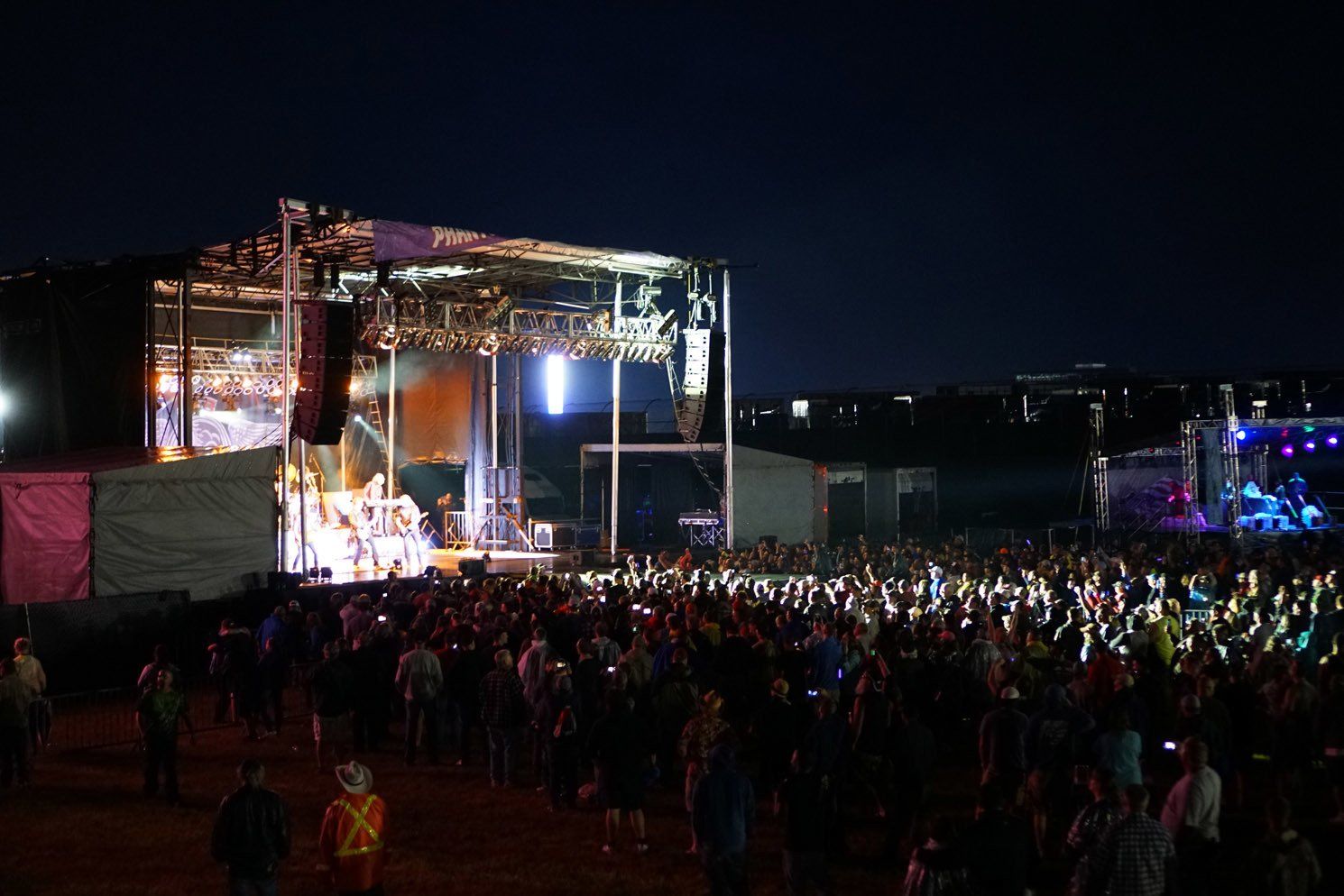 A crowd of people are standing in front of a stage at a concert.