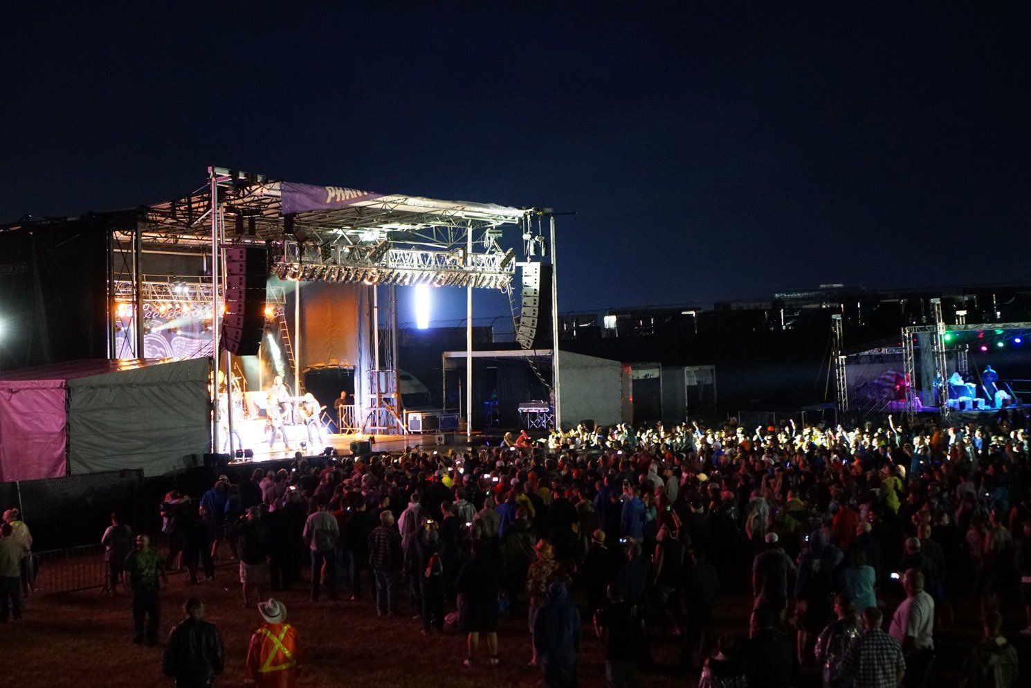 A crowd of people are standing in front of a stage at a concert.