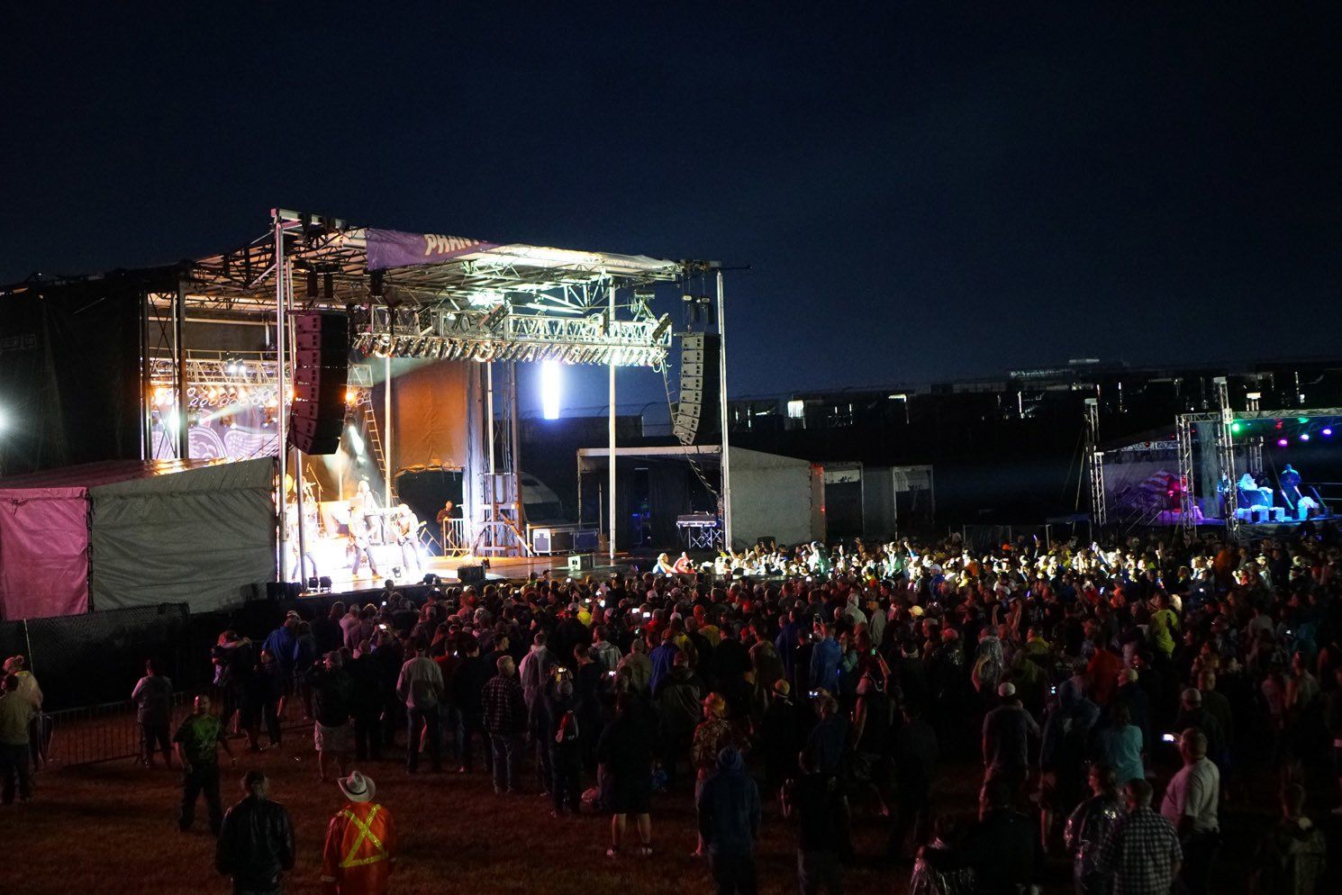 A crowd of people are standing in front of a stage at a concert.