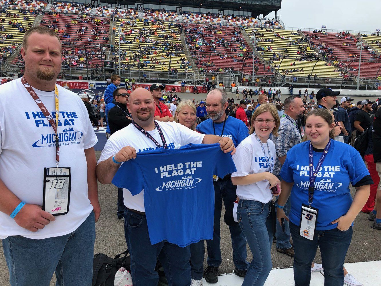 A group of people holding up a blue shirt that says i held the flag at monday