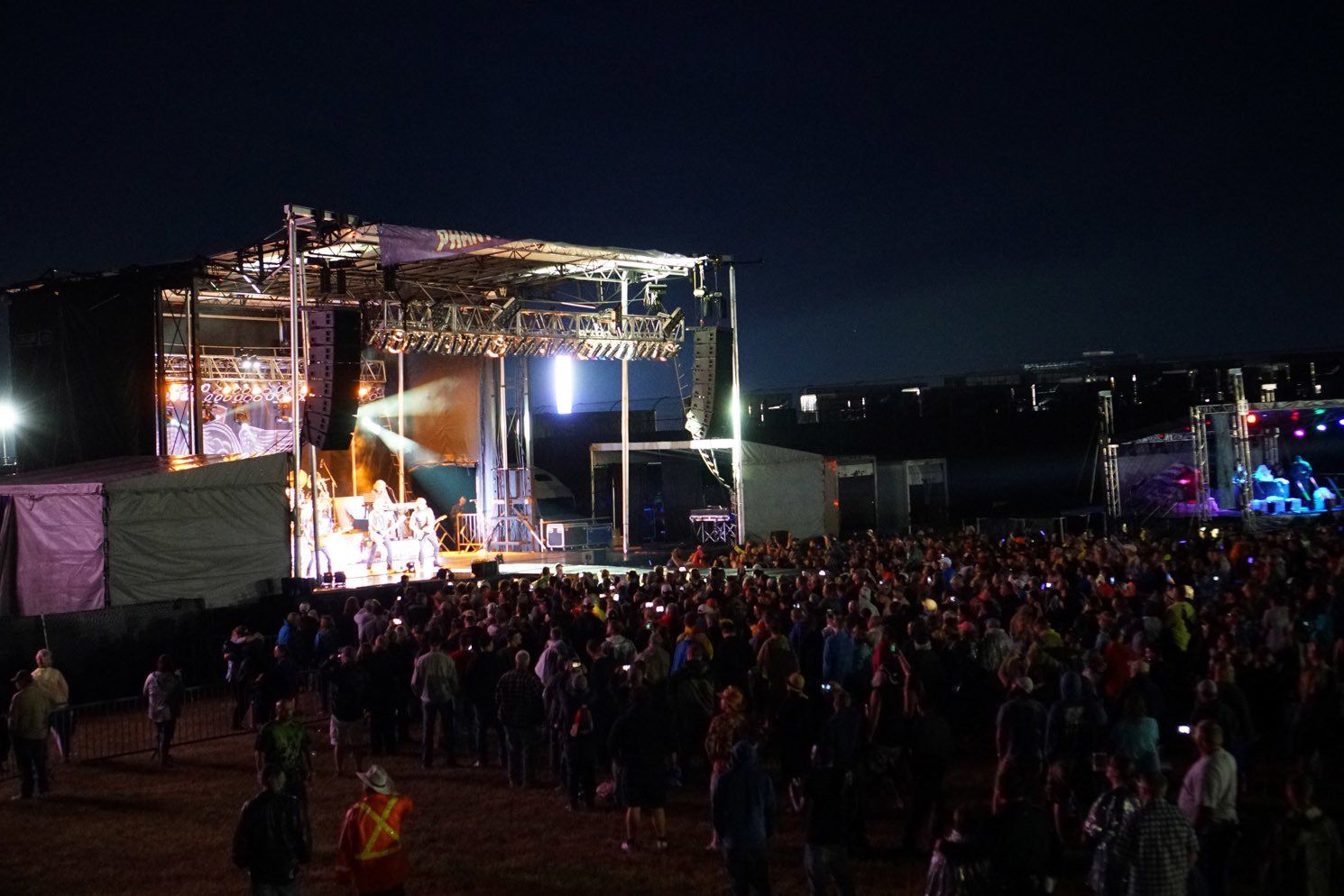 A crowd of people are standing in front of a stage at a concert.