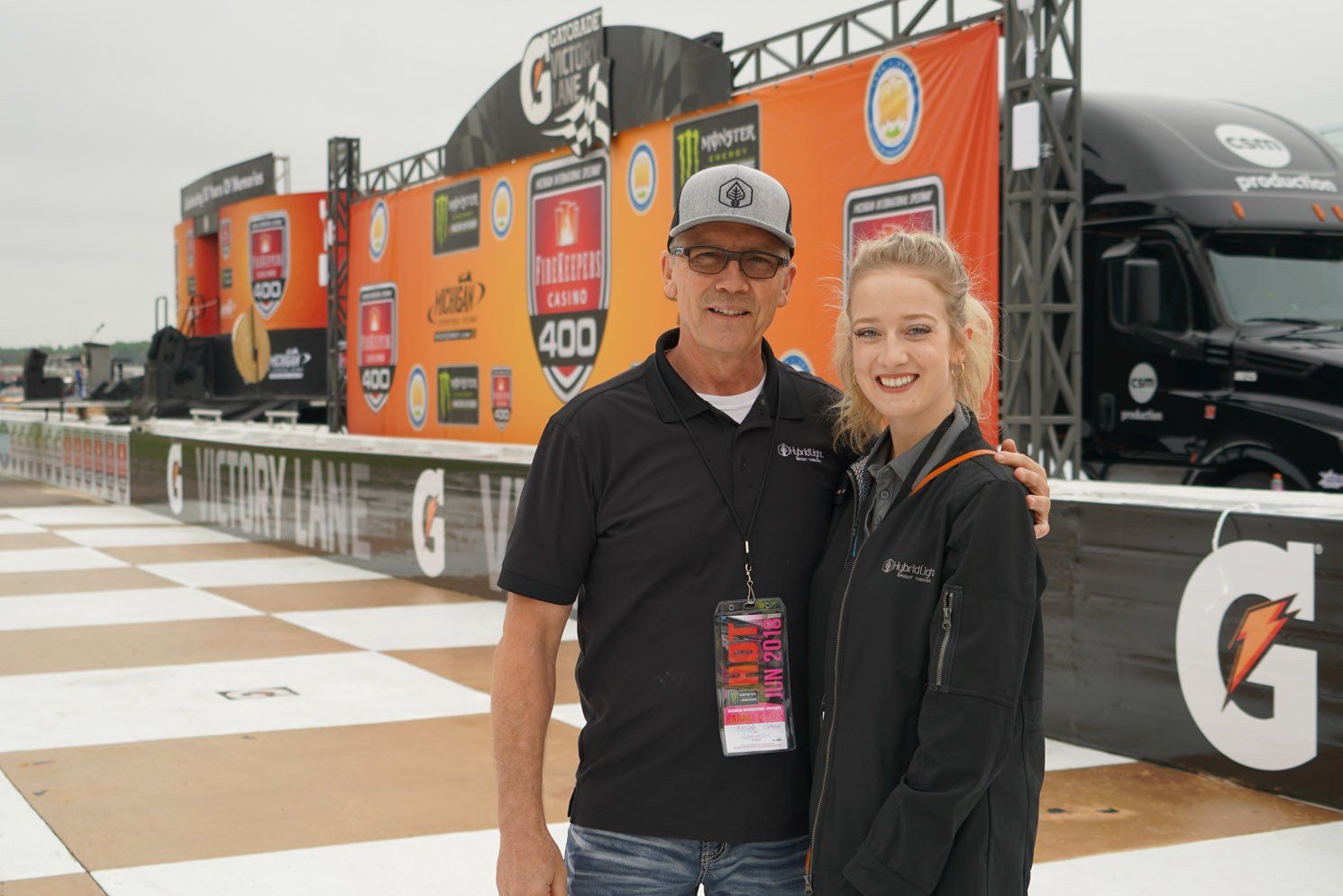 A man and a woman are posing for a picture in front of a gatorade truck.