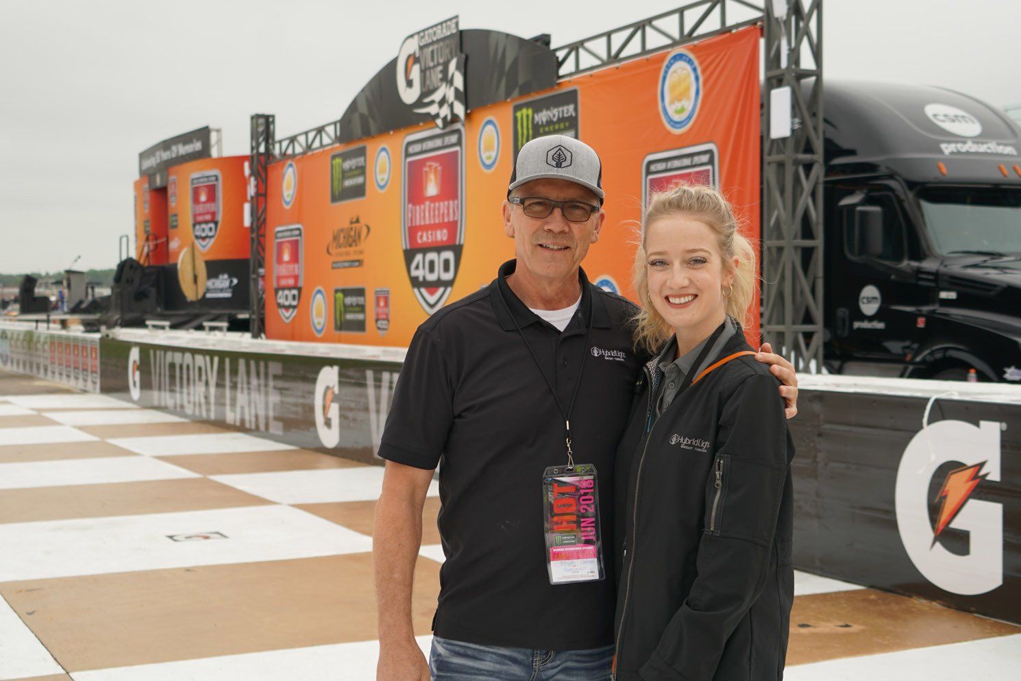 A man and a woman are posing for a picture in front of a gatorade truck.