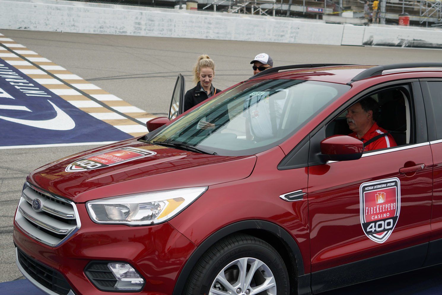 A red ford escape is parked on a race track