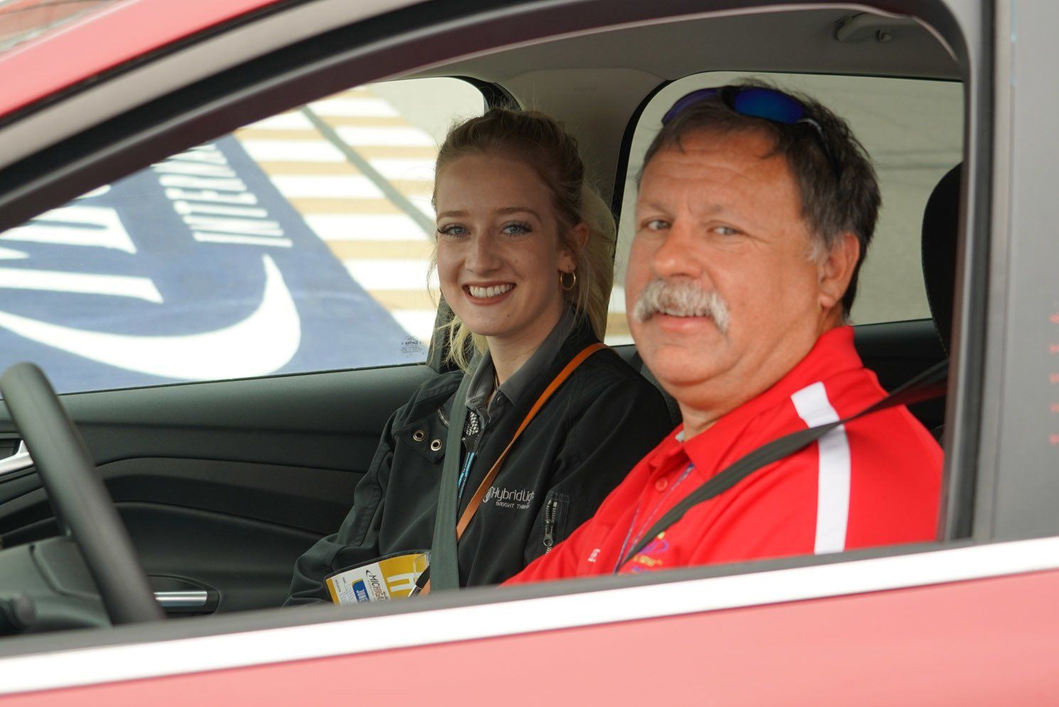 A man and a woman are sitting in a red car