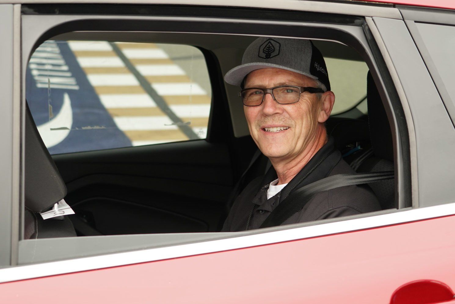 A man wearing a hat and glasses is sitting in a car