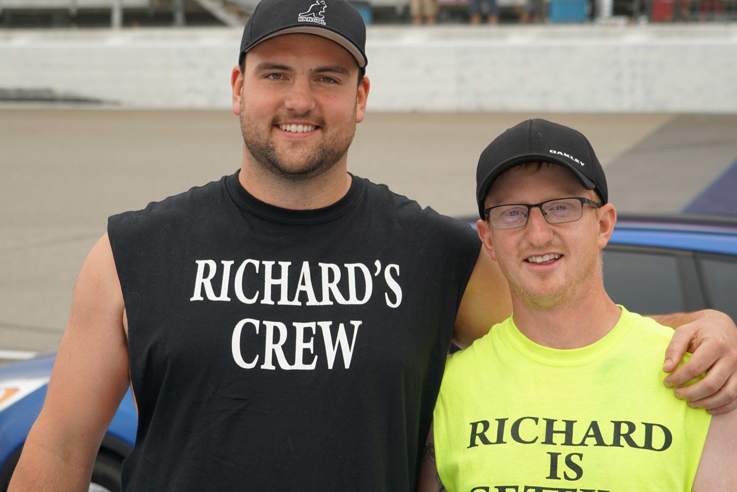 Two men standing next to each other with one wearing a shirt that says richard 's crew