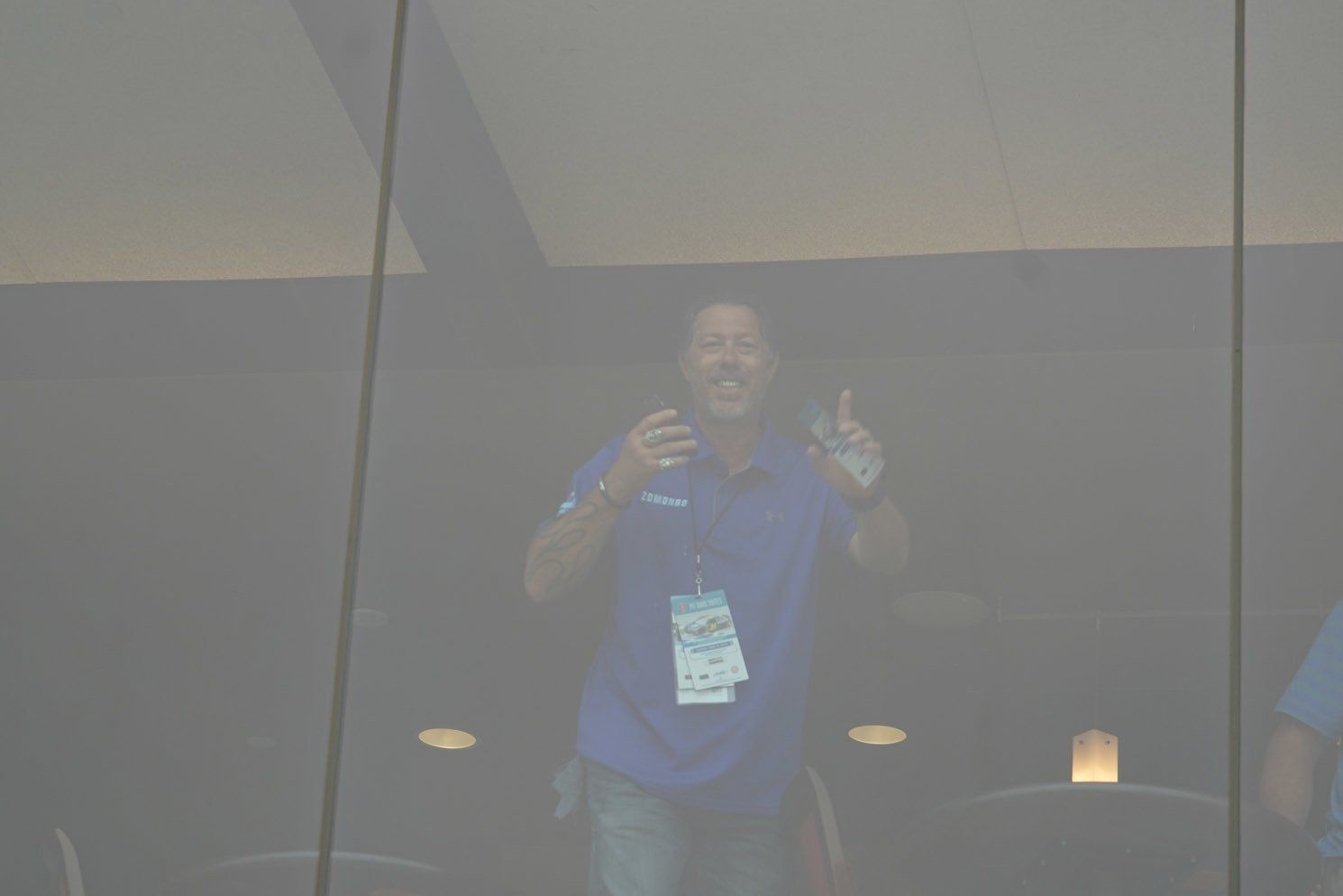 A man in a blue shirt is standing in front of a window.