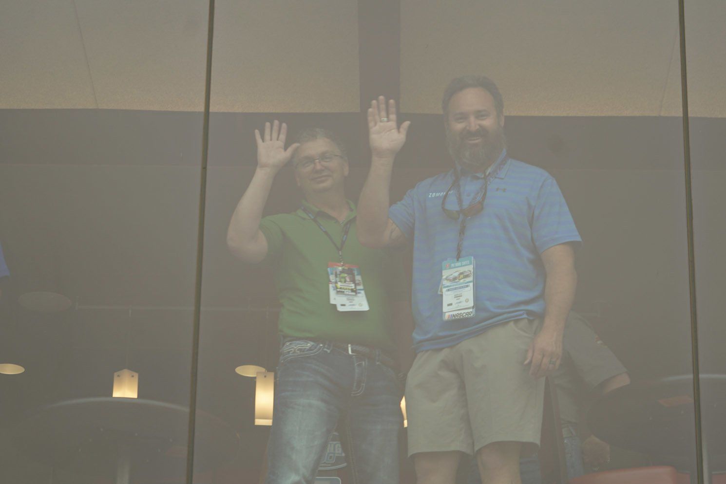 Two men are standing next to each other and waving