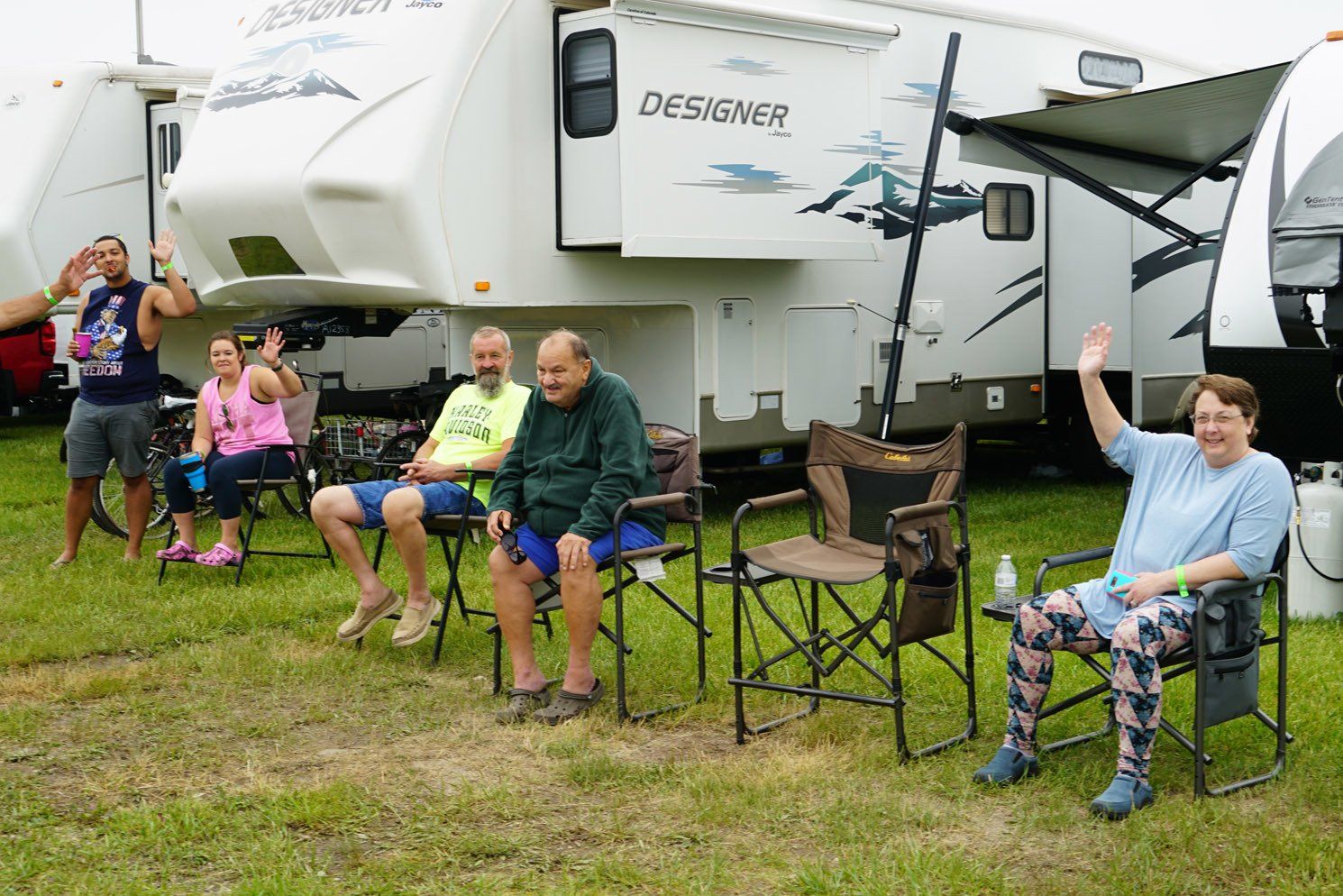A group of people are sitting in chairs in front of a rv.