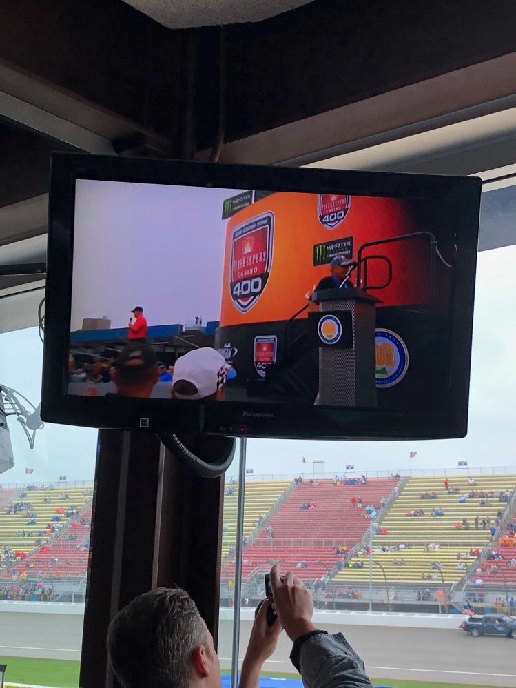 A man is taking a picture of a race on a television