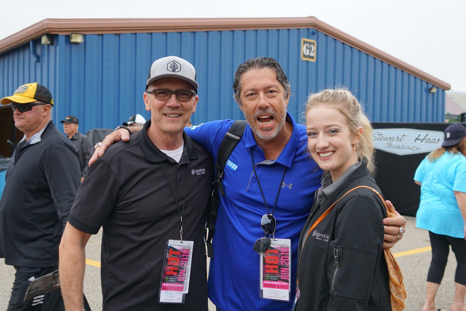 Three people posing for a picture in front of a blue building
