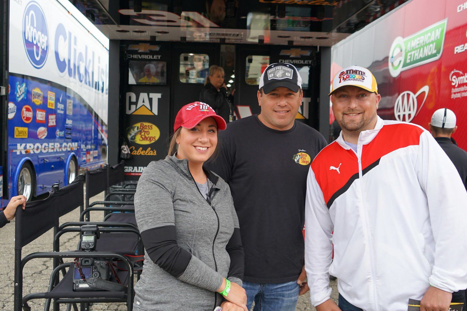 Three people are posing for a picture in front of a cat truck