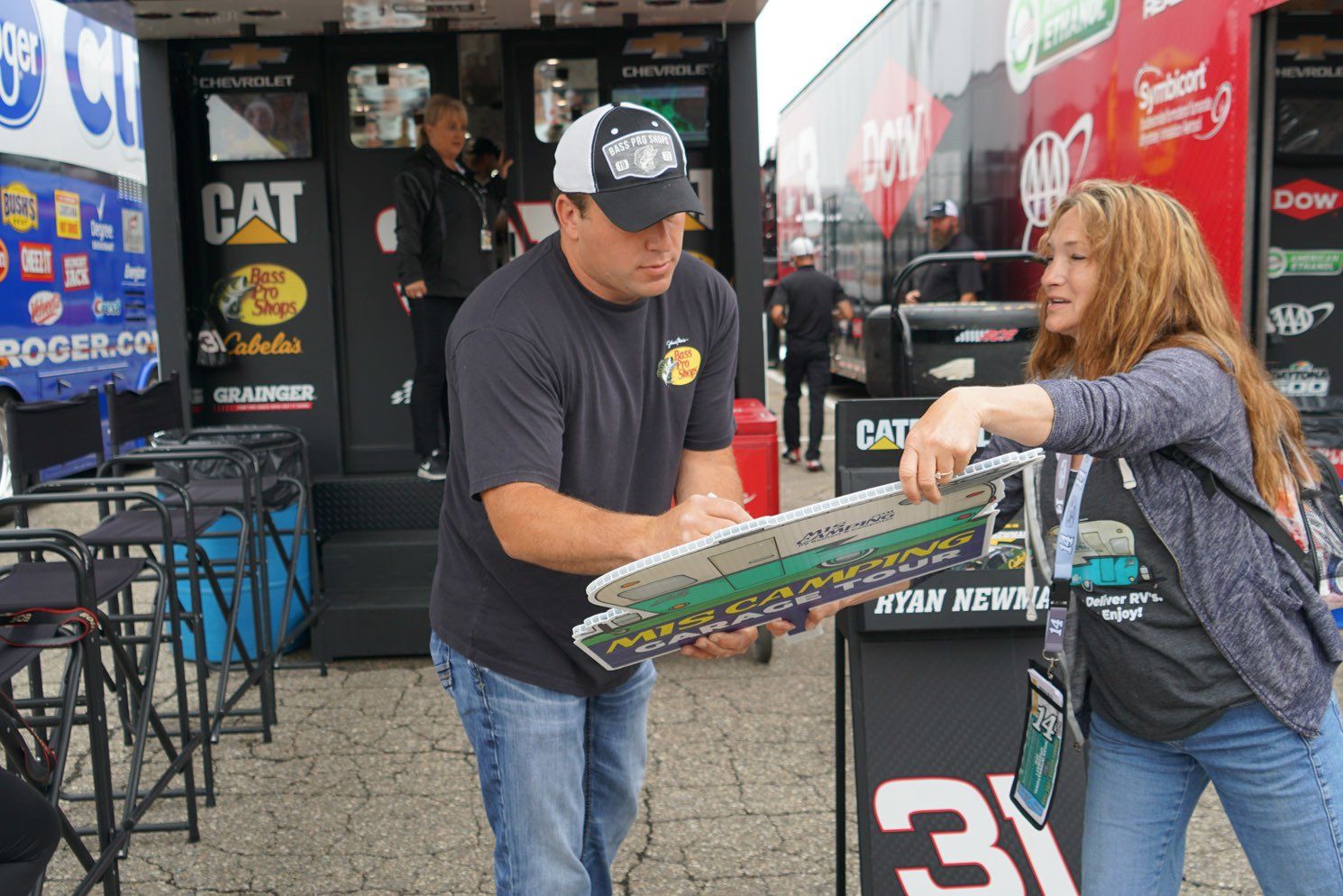 A man and a woman are standing in front of a cat truck